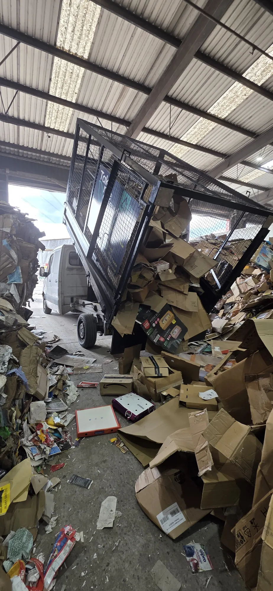 Flattened cardboard tipped from a caged van at a recycling centre