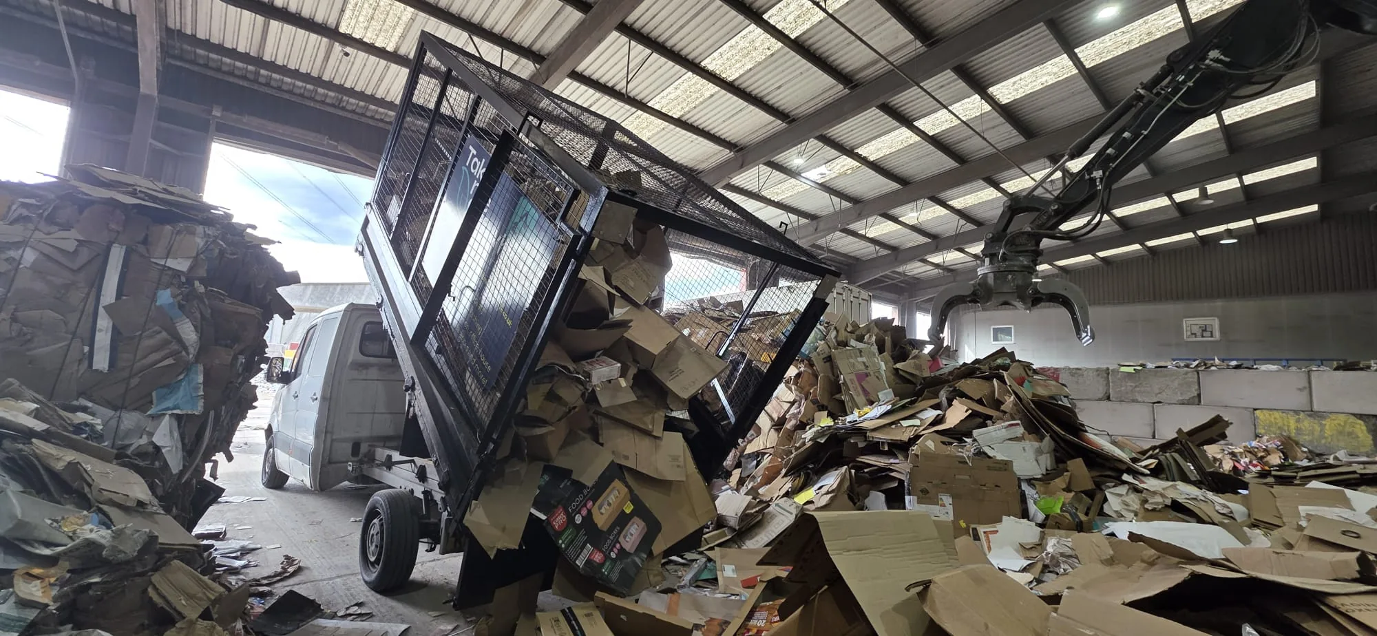 Caged van tipping separated cardboard at a recycling centre