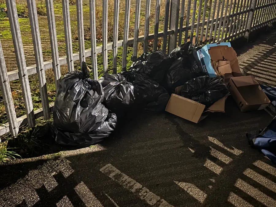 Bags of household items waiting by railings for collection